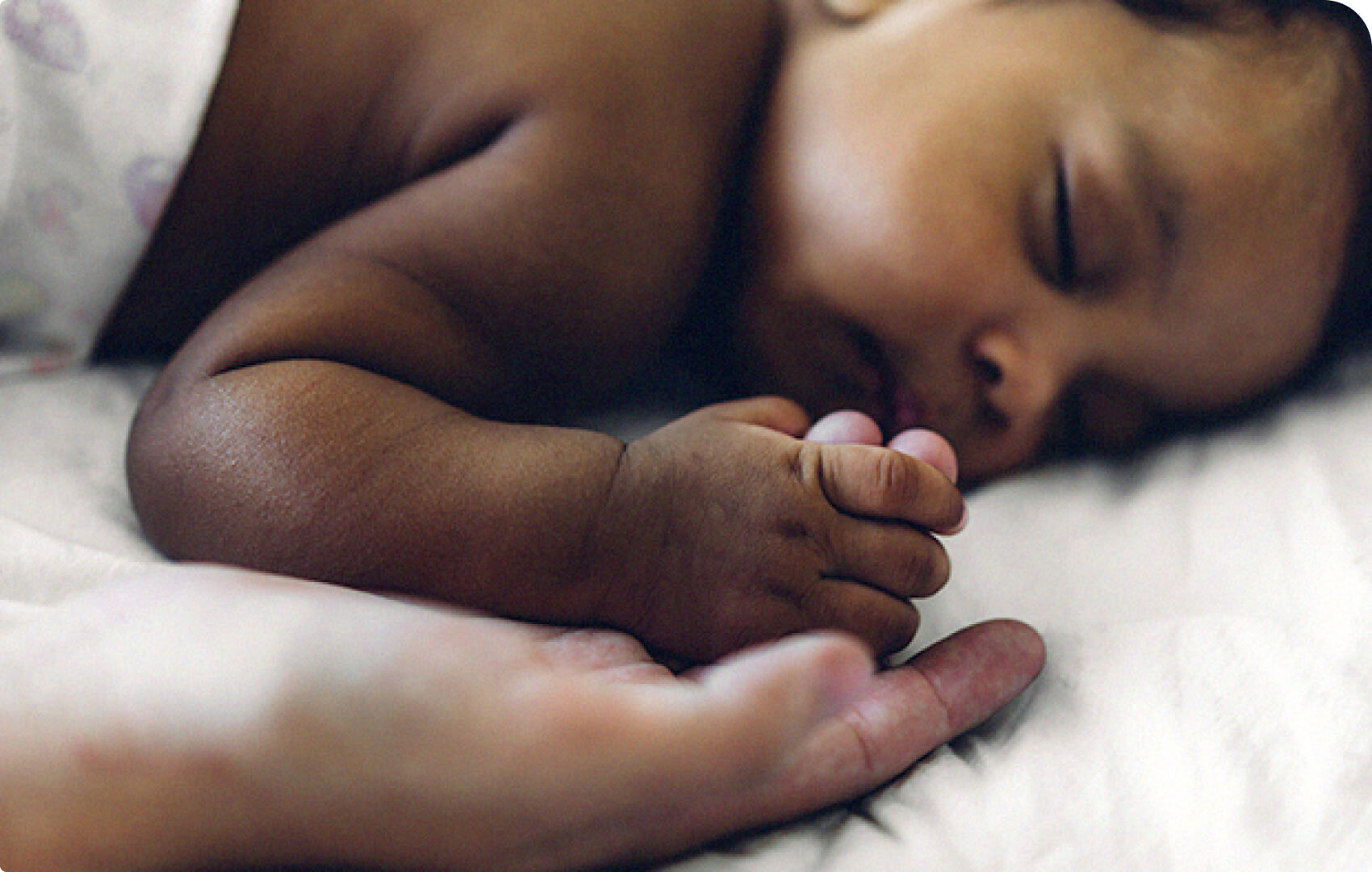 A close-up of a baby holding a parent's hand.