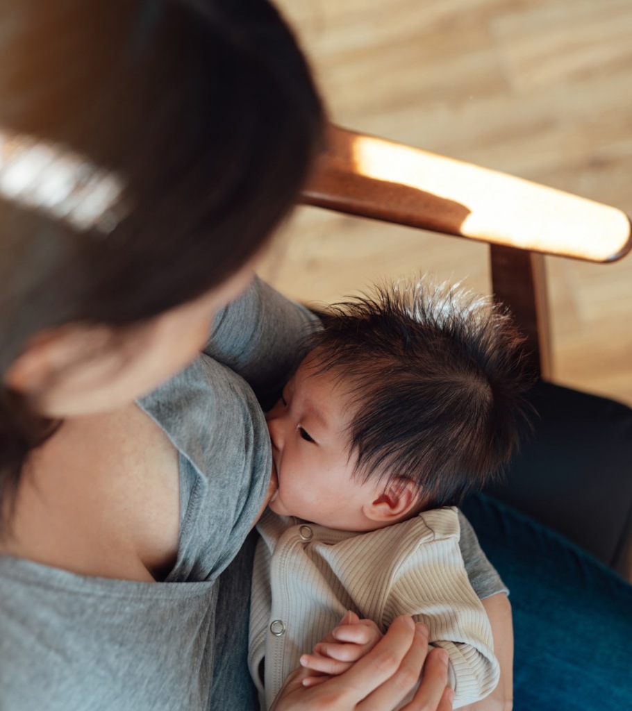 A close-up of a parent cradling their baby while breastfeeding.