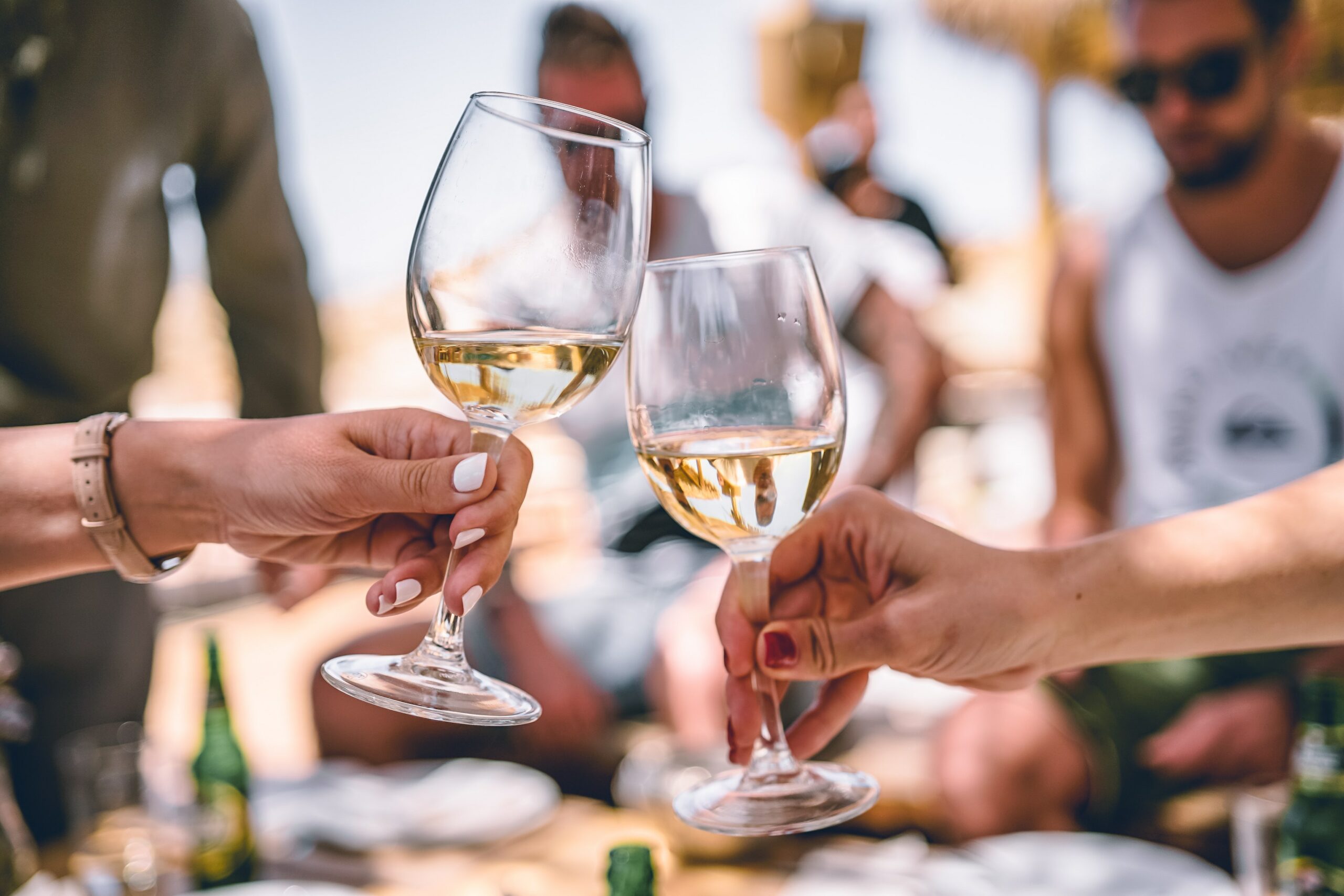 Two hands are shown clinking wine glasses together