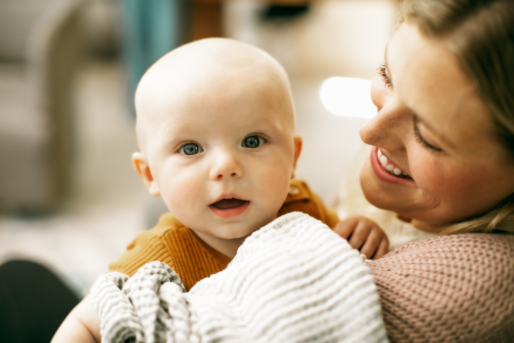 A parent holding their a baby, both smiling joyfully, highlighting the bond between them.