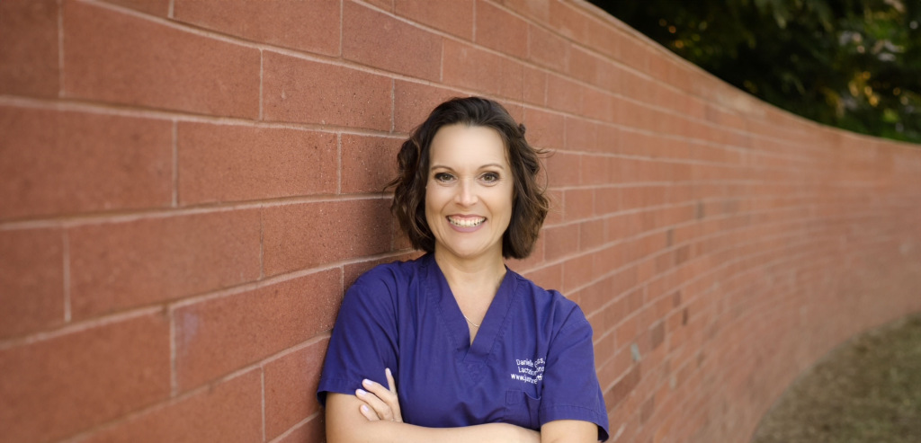 Portrait of Danielle Gauss, IBCLC, leaning beside a brick wall