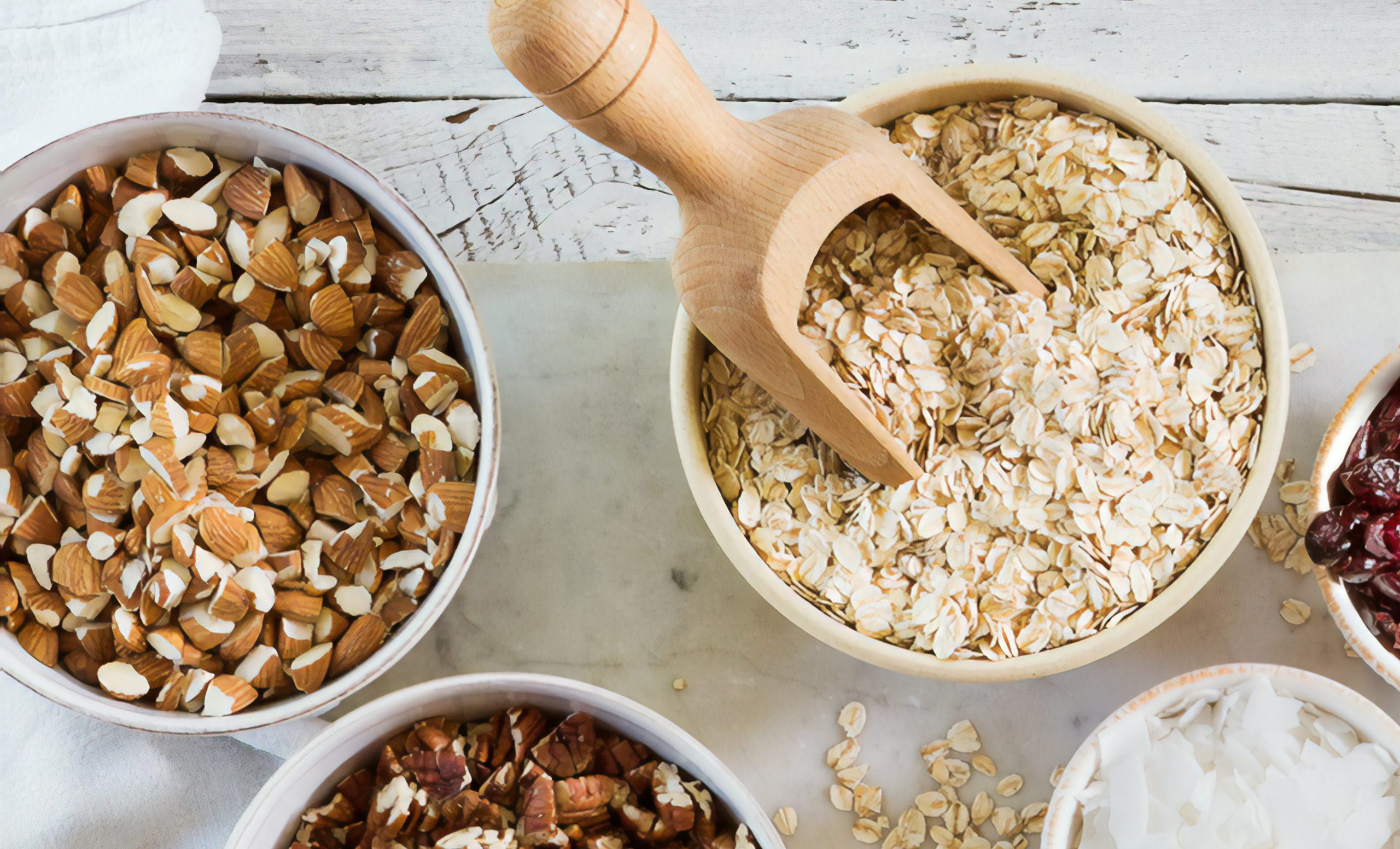 Two bowls are shown, one with dried oatmeal and the other with chopped almonds