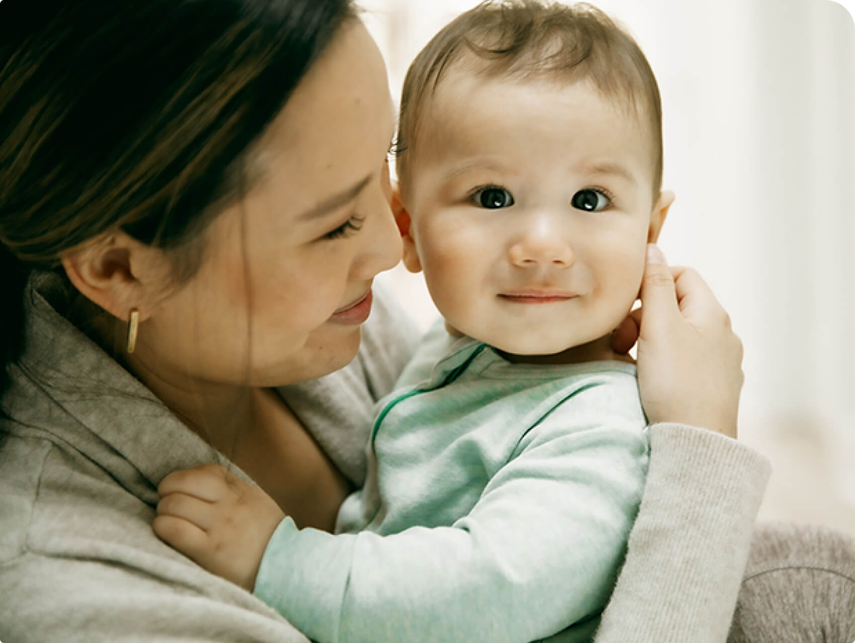 A parent smiling while lovingly holding their baby close.