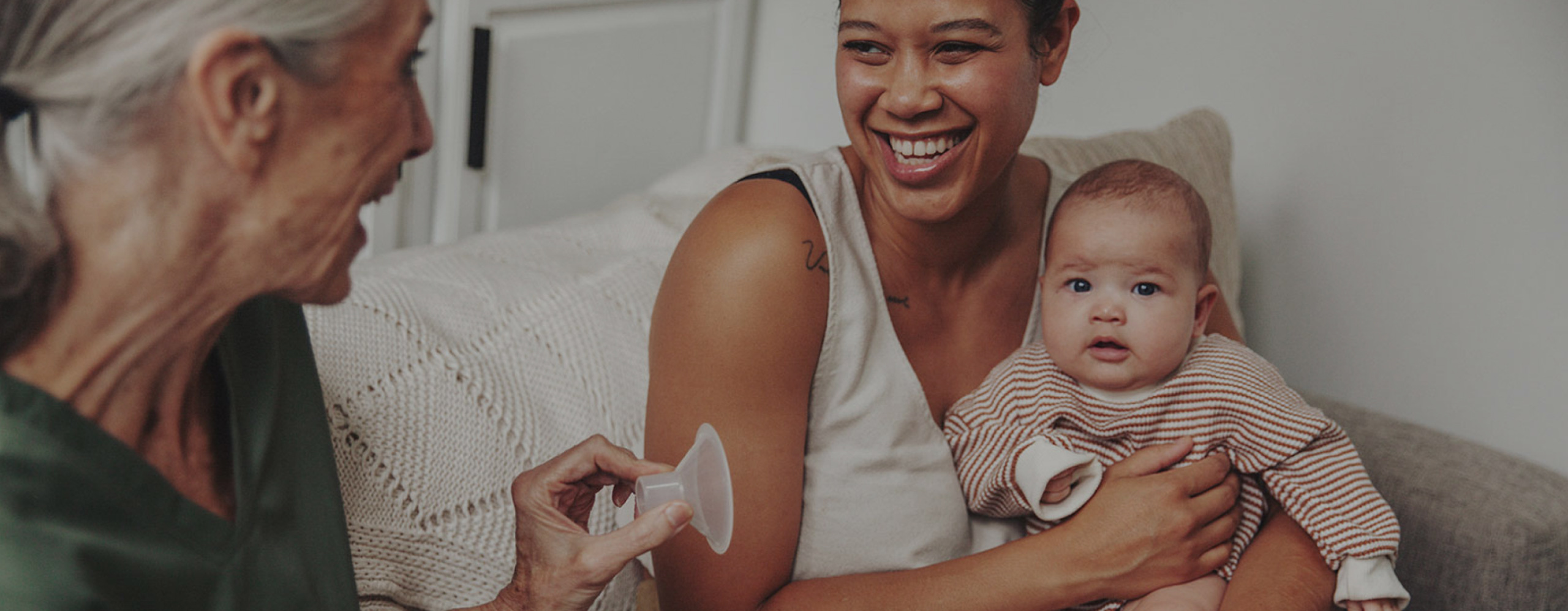 A parent holds their baby while an International Board Certified Lactation Consultant holds a breast pump flange.