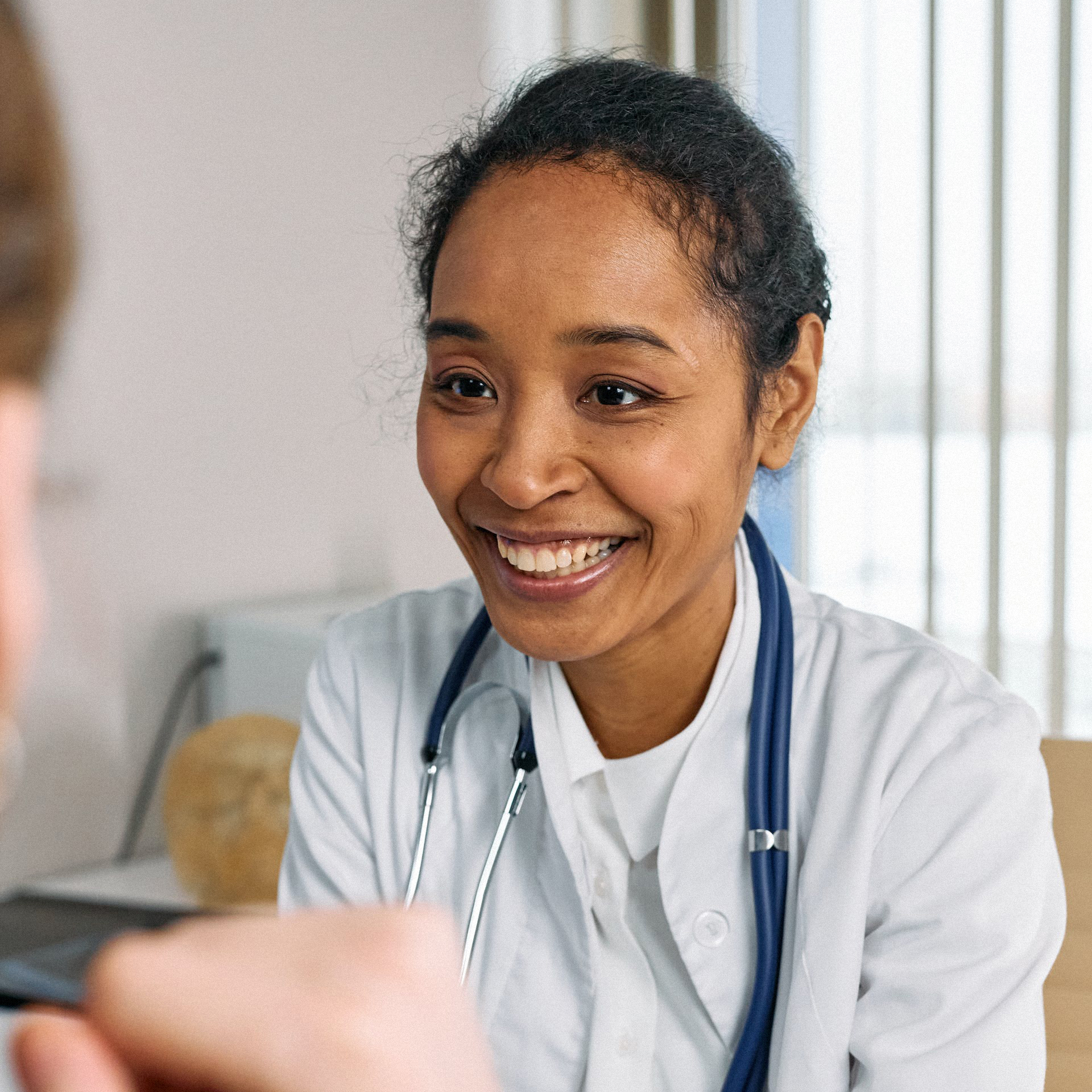 A friendly doctor smiling warmly during a consultation with a patient.