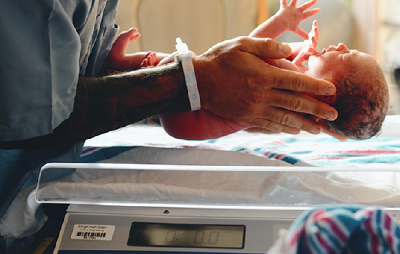 An International Board Certified Lactation Consultant carefully weighs a newborn baby, highlighting the importance of early health monitoring.