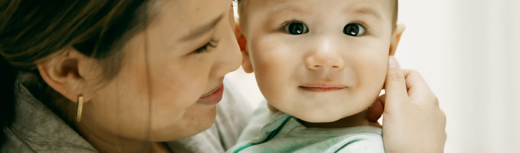 A parent smiling while lovingly holding their baby close.