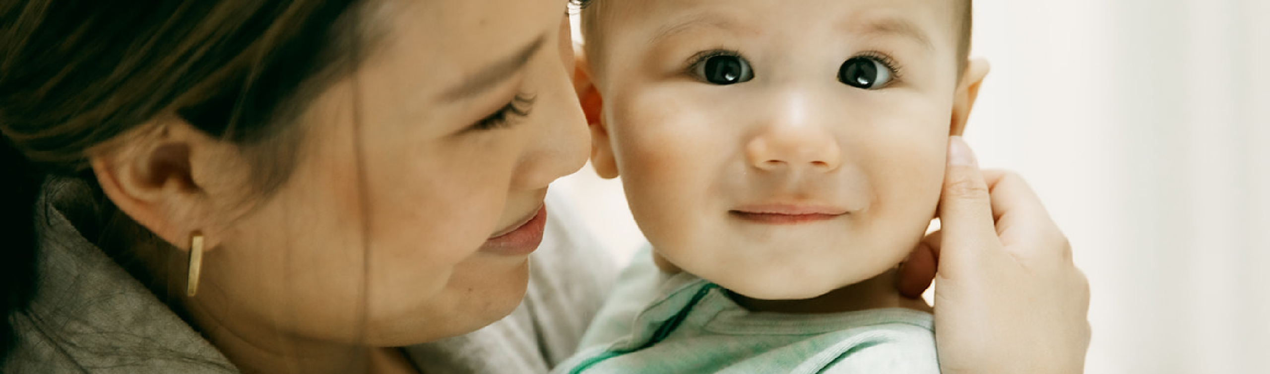 A parent smiling while lovingly holding their baby close.