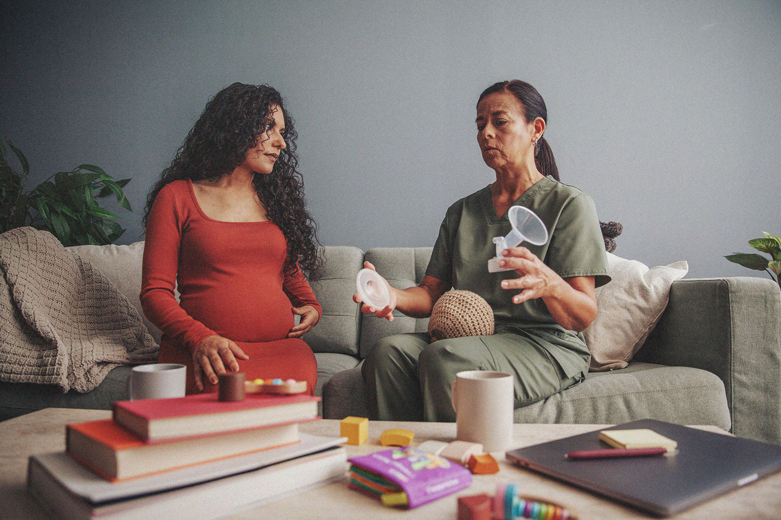A pregnant person listens intently as an International Board Certified Lactation Consultant demonstrates breastfeeding techniques.