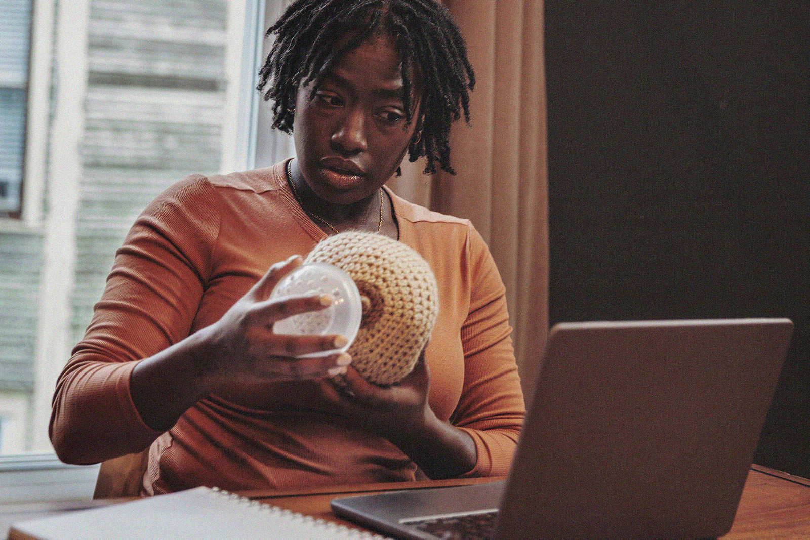 A person learning how to use a breast pump with the help of a knitted breast model while chatting virtually with an expert lactation consultant.