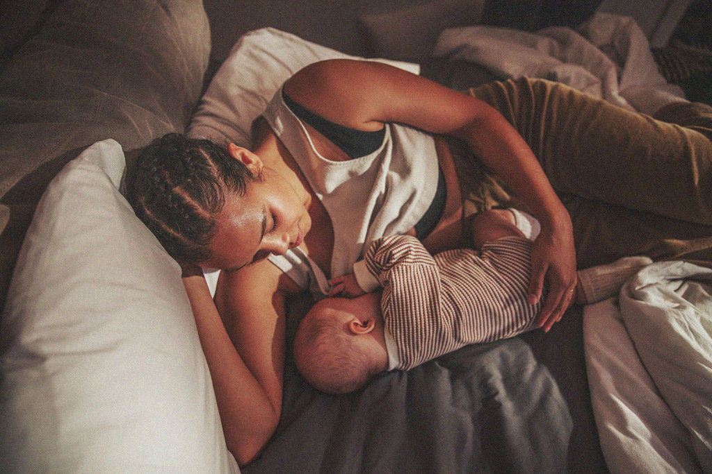 parent lying in bed with nursing baby
