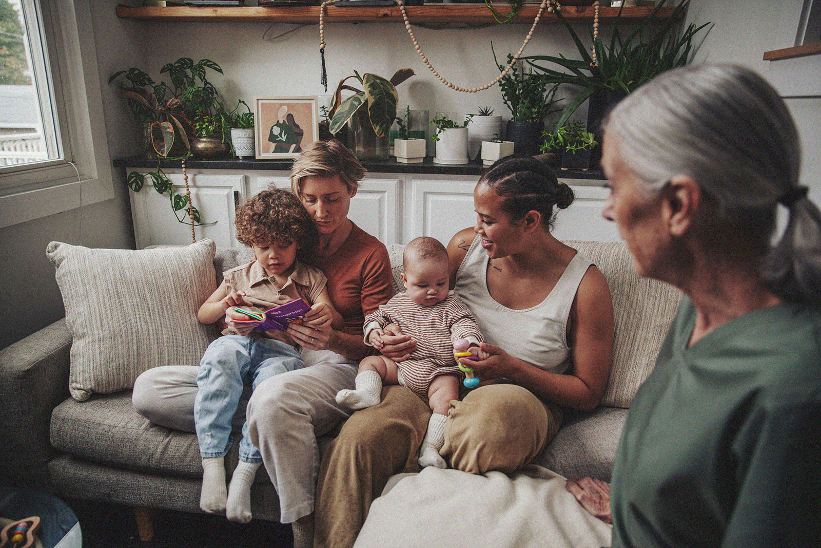 A family relaxing on a couch while interacting with their children.