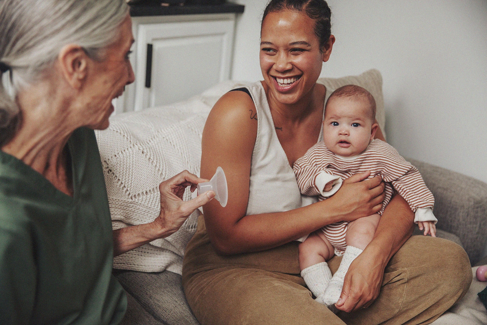 A parent holds their baby while an International Board Certified Lactation Consultant holds a breast pump flange.