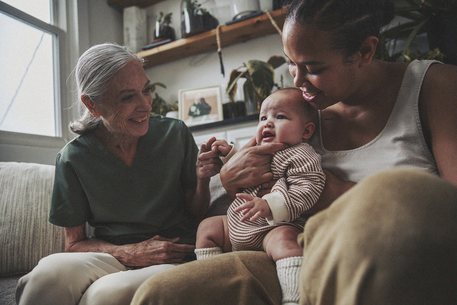 A smiling parent holds their baby while an International Board Certified Lactation Consultant engages with them.
