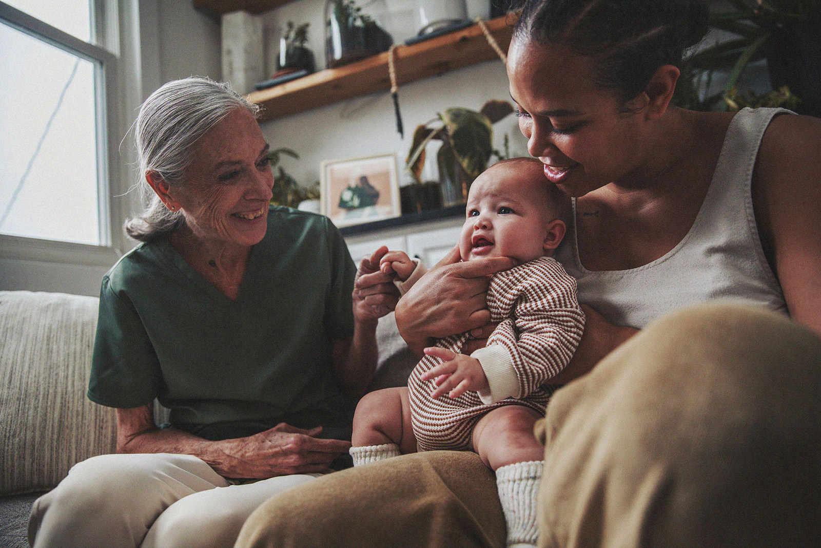 A smiling parent holds their baby while an International Board Certified Lactation Consultant engages with them.
