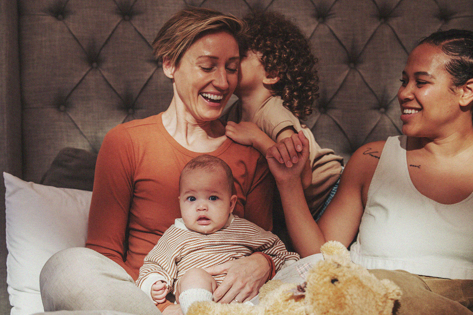 Parents and their children enjoying quality family time on the bed.