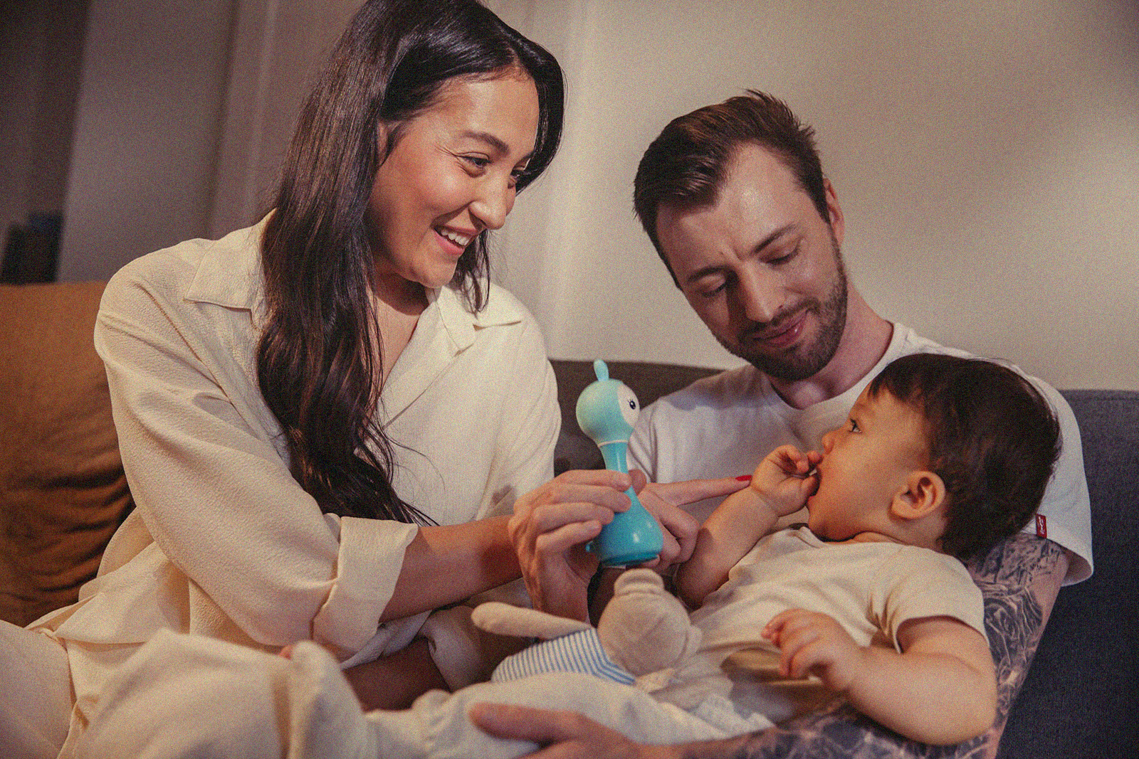 Parents playing with their toddler using a toy, highlighting a joyful family interaction.