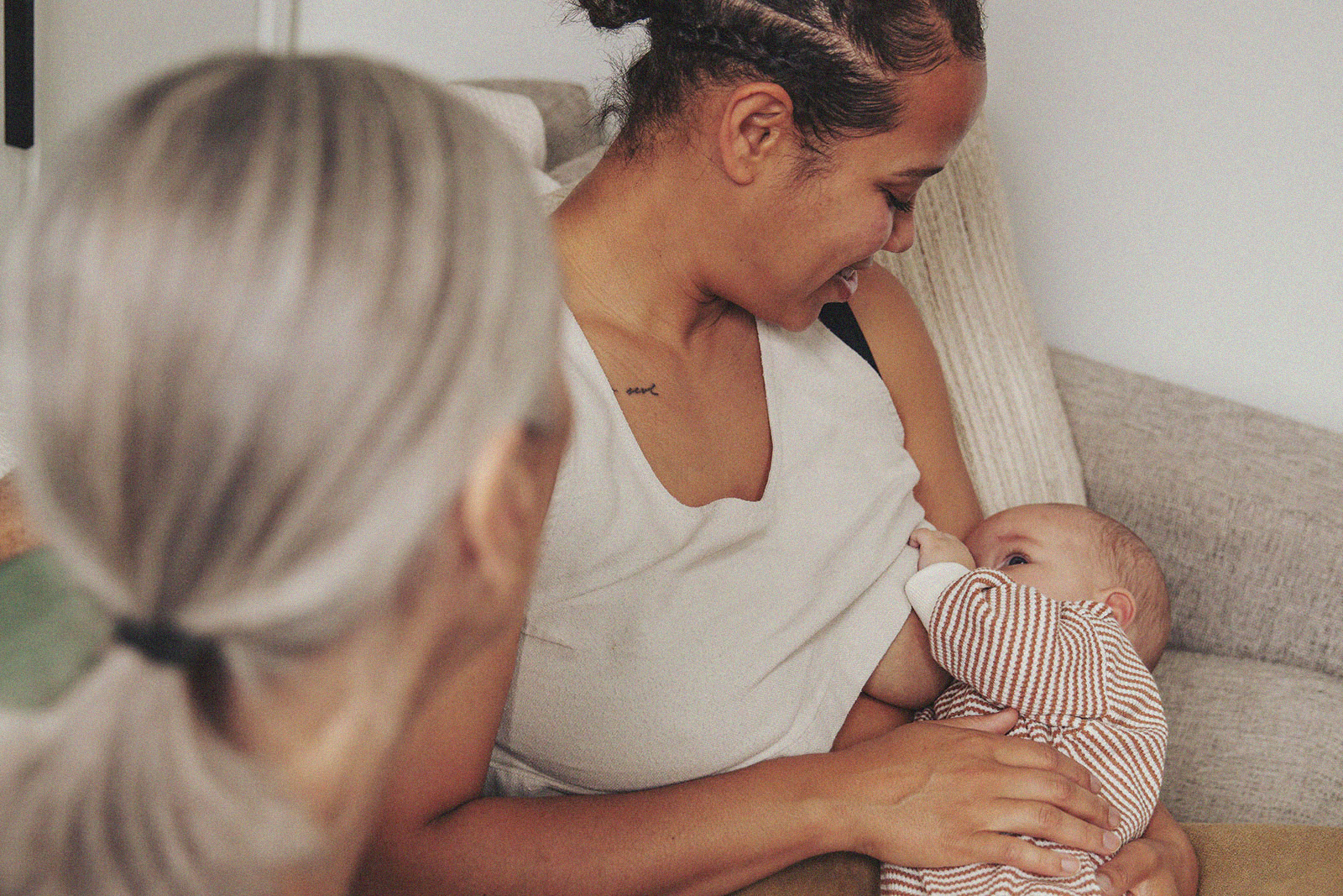 A parent breastfeeding their baby while an International Board Certified Lactation Consultant observes.