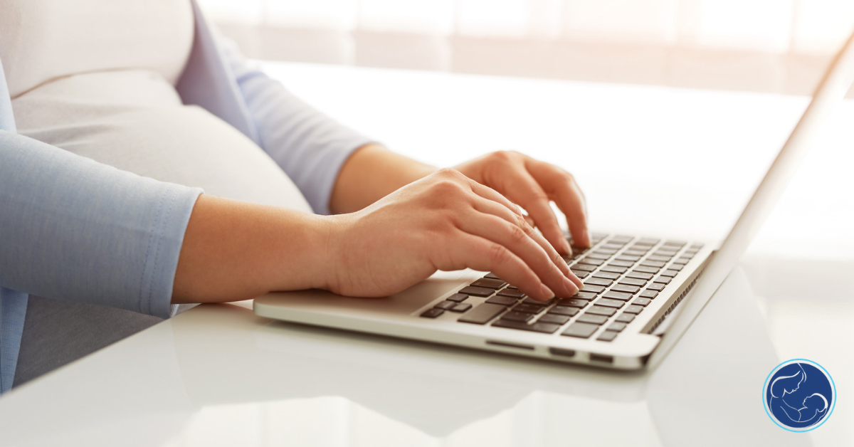 A person types on their laptop while seated at a table.