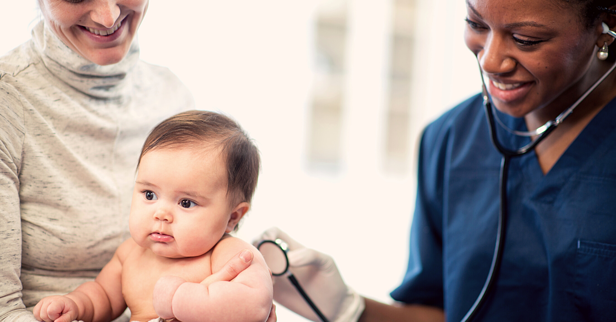 A clinical care provider presses a stethoscope to the back of a baby during a health care visit while the parent holds the baby