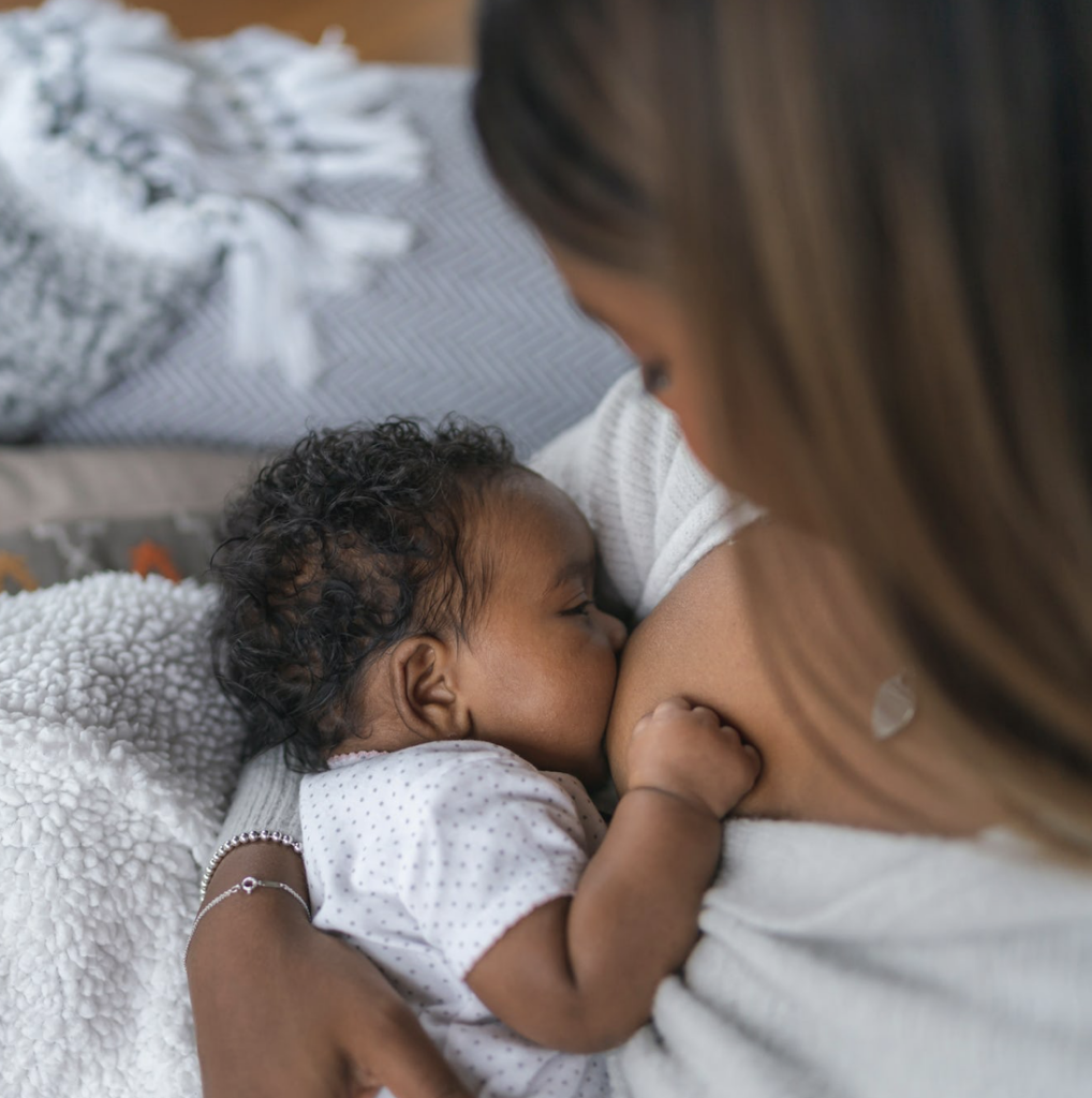 A close-up of a parent breastfeeding their baby in a comfortable setting.