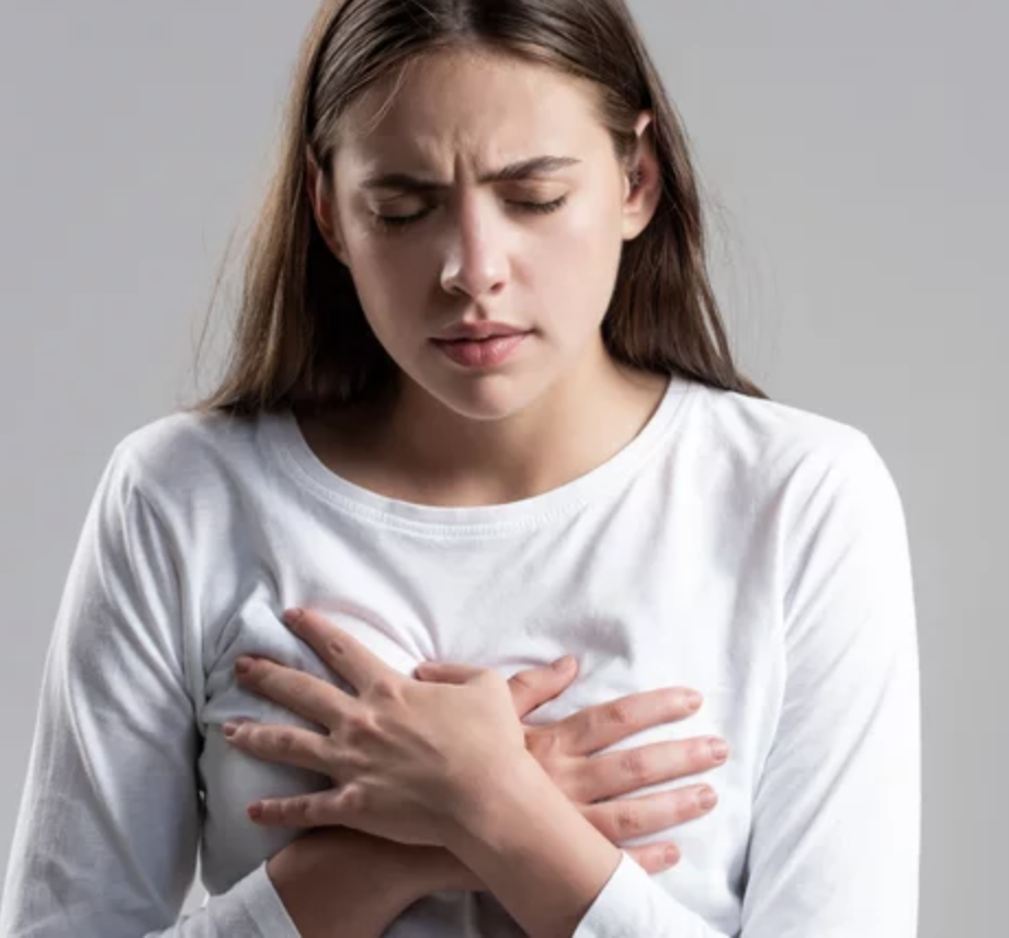 A person expressing discomfort, clutching their chest, possibly indicating difficulty with breastfeeding.