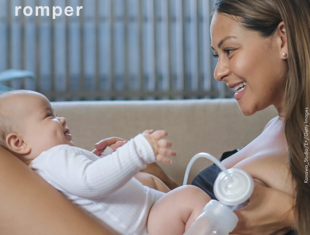 A parent pumping breast milk while smiling at their baby.