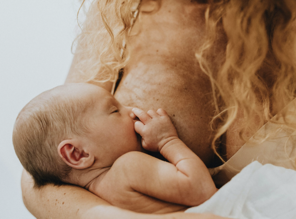 A newborn baby breastfeeding from a parent, showing their bond through breastfeeding.