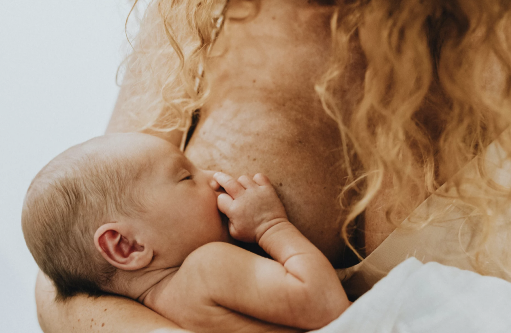 A newborn baby breastfeeding from a parent, showing their bond through breastfeeding.