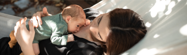 A parent and baby resting together in a hammock, with the baby gently resting on the parent's chest.