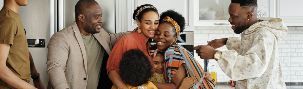 A joyful family gathering in the kitchen, with members embracing and sharing a moment of happiness together.