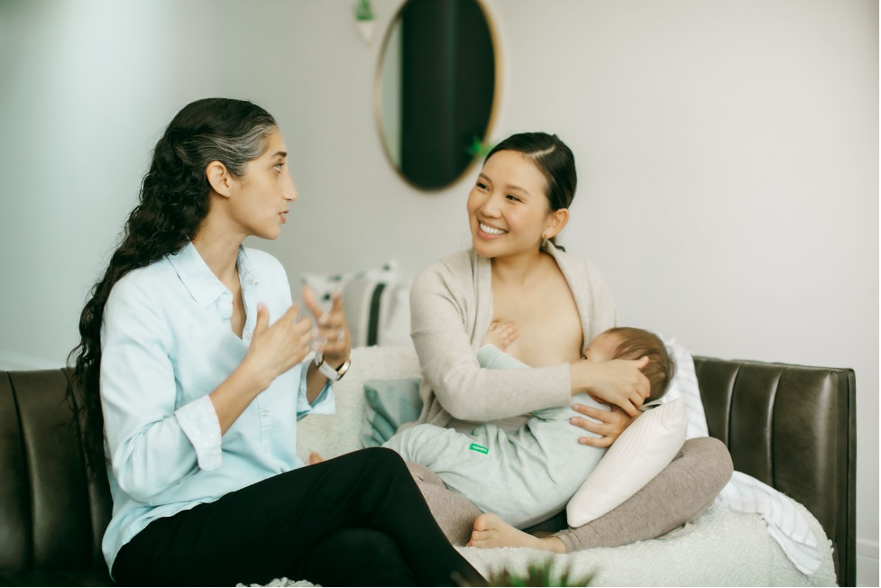 parent smiles while feeding baby during lactation consult